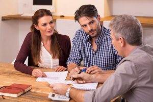 Businessman explaining loan policy to young couple. Happy young